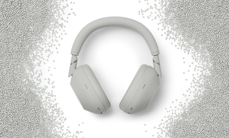 Silver WH-1000XM6 headphones crafted from recycled materials, surrounded by white plastic pellets.