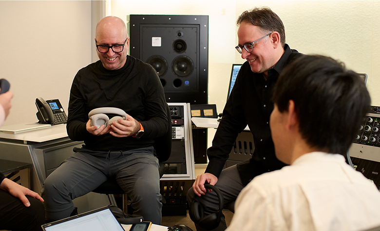 Group of audio engineers testing headphones in a recording studio.