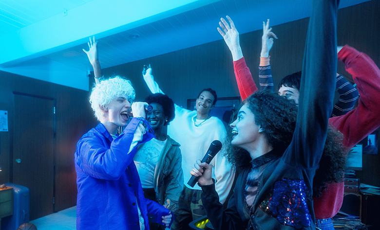 2 people singing into their ULTMIC1 with their friends dancing next to them