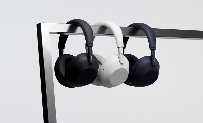 Three WH-1000XM6 pairs of headphones hanging on a display bar in different colours: black, platinum silver, and midnight blue.