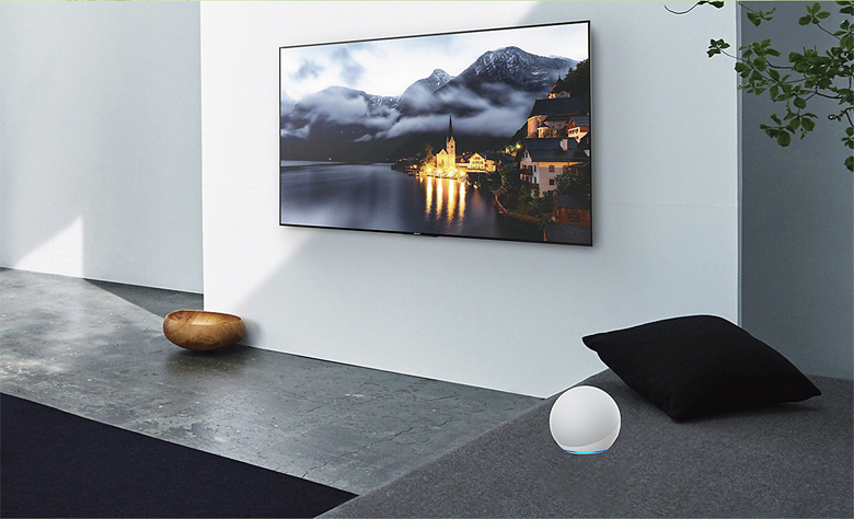 Living room scene showing a TV on the wall with an Alexa device to the side.