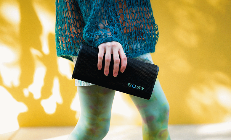 A person walking down the street with the ULT FIELD 3 speaker in their hand