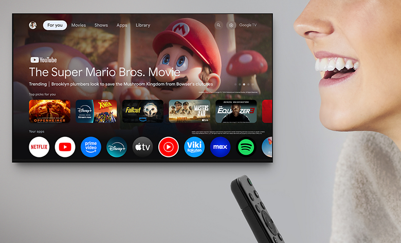 Close-up of a person holding a remote and using voice to control the TV.