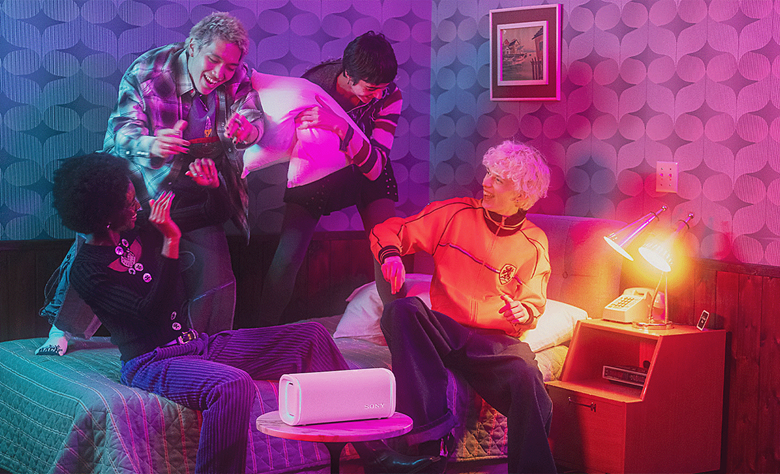 Four people in a room having fun with the ULT FIELD 5 speaker on a table in front of them