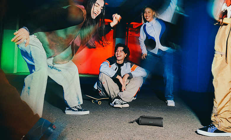 A group of young people dancing around the ULT FIELD 1 Portable Speaker.
