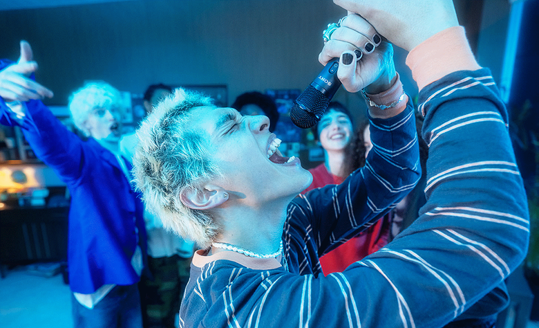 A person singing into the ULTMIC1 with their friends watching in the background