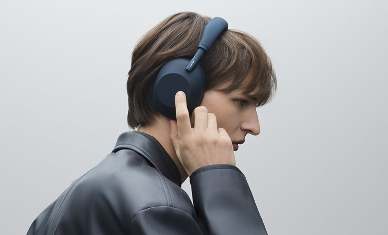 Profile view of a person tapping their WH-1000XM6 headphones.